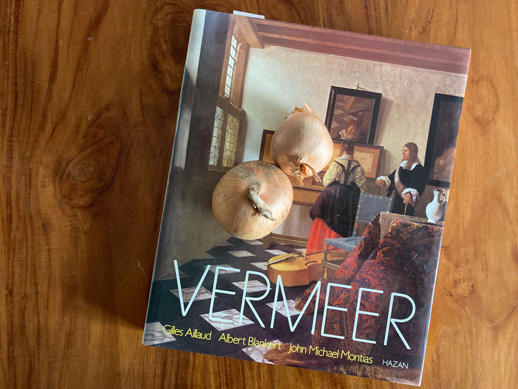 Kunstkatalog über Johannes Vermeer. Darauf liegen zwei Zwiebeln.