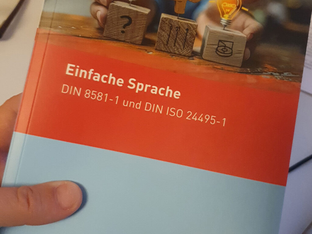 Jemand hält das Handbuch mit den Einfache-Sprache-Normen für mehr Verständlichkeit in der Hand.
